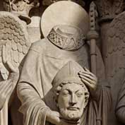 St Denis' statue in Notre-Dame Cathedral, Paris. He was beheaded around 250 AD - Notre-Dame was built on the site of his church 900 years later. A relic of St Denis, placed in the weather vane atop the cathedral's spire in the 1830s was lost in the devastating fire of 15th April 2019. [Photo by Thesupermat-CC BY-SA 3.0, https://commons.wikimedia.org/w/index.php?curid=21763309]