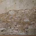 Part of the south wall in the nave of St Denis' church, East Hatley, Cambridgeshire in December 2021 showing the poor sate of the plasterwork, much of which had crumbled away to expose the building's field stone construction. The building is owned by the Friends of Friendless Churches and thanks to a second grant from the UK government's Culture Recovery Fund, the FoFC was able to replaster the wall and complete other restoration work inside the church in spring 2022. St Denis' is now every day from 8.30 am to dusk. Photo: Peter Mann / Buzz Associates.